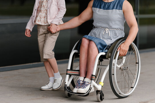 Crop woman on wheelchair riding near daughter