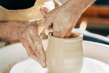 Caucasian man making vessel daytime of white clay in fast moving circle