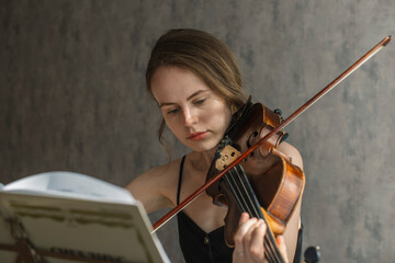 A beautiful woman plays the violin at home