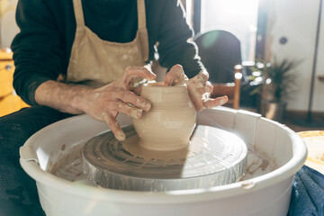 Cropped view of the potter making clay water pot on pottery wheel