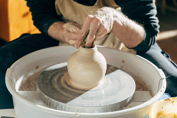Male brunette sculpt a utensils near wooden table with tools