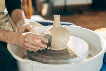 Happy european artisan man creating ceramic piece on spinning pottery wheel
