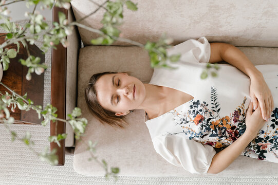 Young woman in embroidered dress resting on sofa
