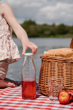 Crop girl with bottle of berry drink having picnic