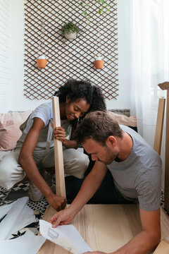 Young multiethnic couple installing furniture together