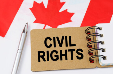 Against the background of the flag of Canada lies a notebook with the inscription - CIVIL RIGHTS