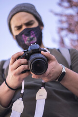 young man with mask taking photos outdoors with professional camera