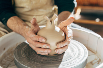 High angle view of man making ceramic pot on the pottery wheel