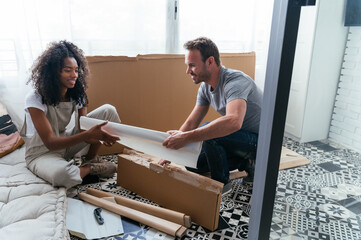 Young couple unpacking new furniture at home