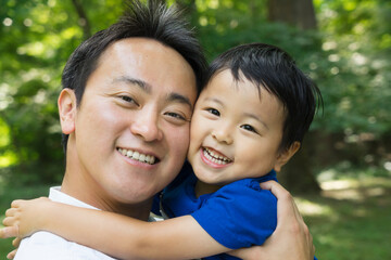 Smiling Asian father and boy portrait in green