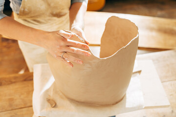 Woman making by hands big brown clay pot or vase