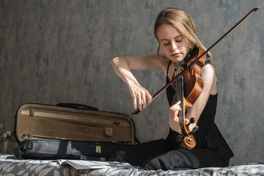 A beautiful woman plays the violin at home