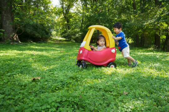 Asian siblings playing with toy car in the park