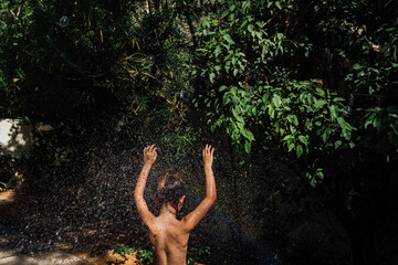 Girl under water drops in the garden