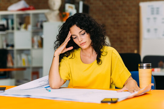 Worried businesswoman looking at blueprints in an office