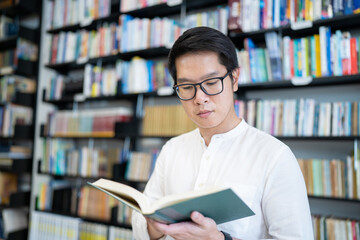 A man is reading a book in the university library.