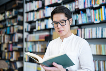 A man is reading a book in the university library.