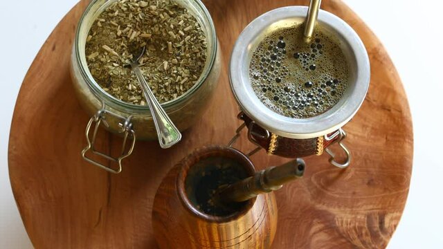 Yerba mate, A natural infusion of holly leaves. Vessels slowly rotating on a wooden tray with a bombilla for drinking traditional South American tea 