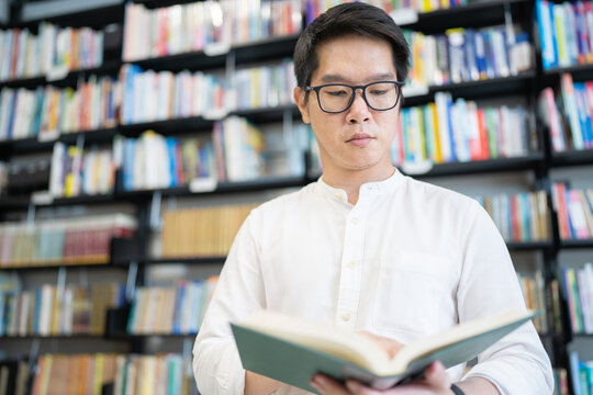 A man is reading a book in the university library.