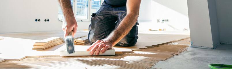Handwerker verlegt parkettboden in einem Haus.