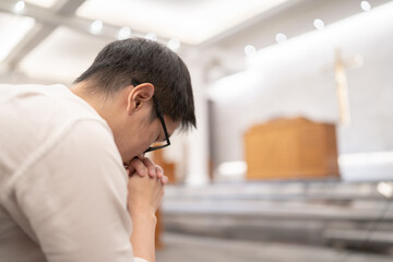 Fototapeta premium A man praying on a bench in a Christian church.