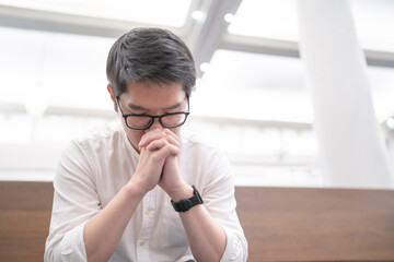 A man praying on a bench in a Christian church.