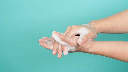 Hands washing gesture with foaming hand soap on green and Tiffany Blue  background.