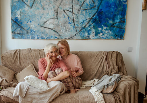 Active age ageless senior woman with daughter on house sofa