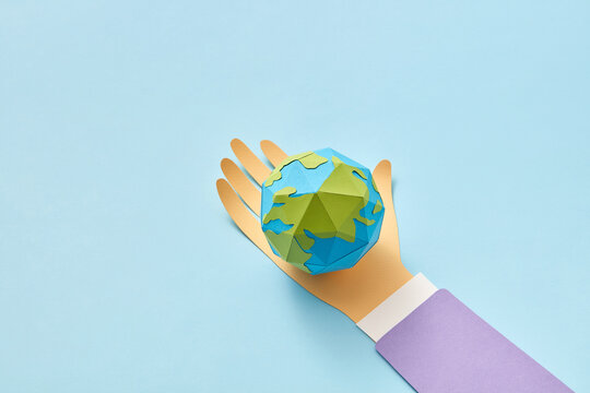 Paper hand holds handmade Earth's globe.