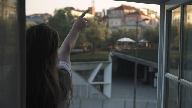 Girl looking out of a window in Porto, pointing at something