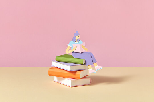 Papercraft girl is sitting on the books and reading.