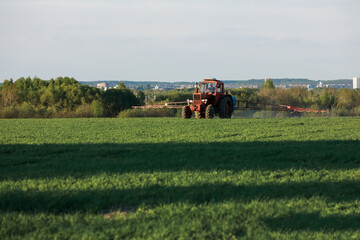 Farmer on tractor cultivates a field plantation. Fertilizer with