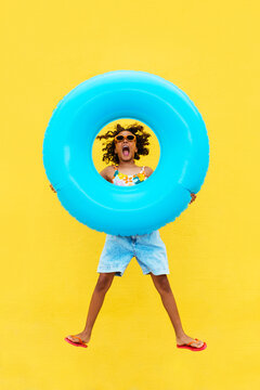 Excited ethnic girl jumping with inflatable ring