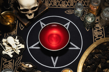Ritual bowl with blood on the table. Mystic background with occult and magic objects on ritual...