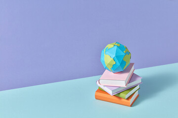 Papercraft Earth's globe on a stack of study books.