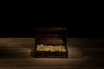 Open ancient trunk with golden coins on a dark background. Chest of pirate treasure. 