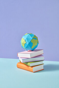 Papercraft stack of study books and Earth's globe.