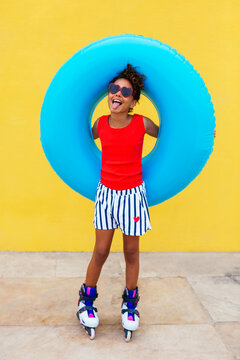 Happy black girl with swim tube on roller skates