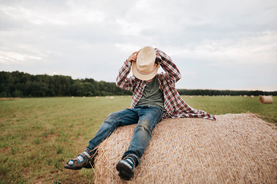 Portrait of a little boy in a hat on a haystack.