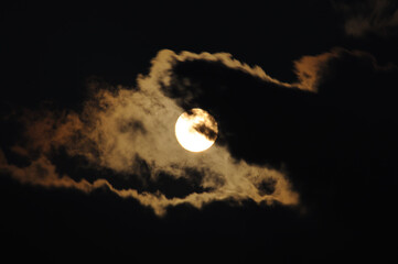 Full moon close-up and eerie white clouds against a black night sky. The big moon on a dark night The clouds gather together in various images. Full moon with dramatic clouds in the night sky. 