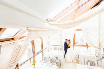 the newlyweds are hugging in the restaurant hall. profile. beaut