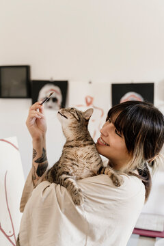 Young female artist with cat painting on her studio