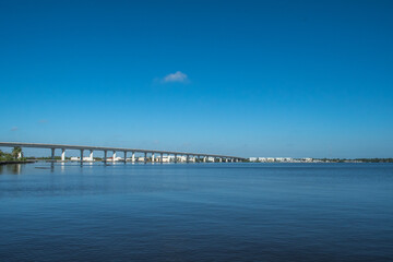 Fototapeta na wymiar Roosevelt Bridge near downtown historic Stuart, Florida. Blue water, blue sky with a single cloud. Peaceful scene for this eastern Florida waterfront town.