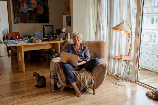 Active age ageless elderly woman working from home on a laptop