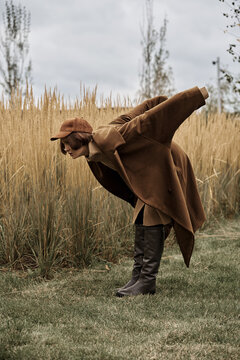 Fashionable fashionable woman in a brown coat is standing in the field.