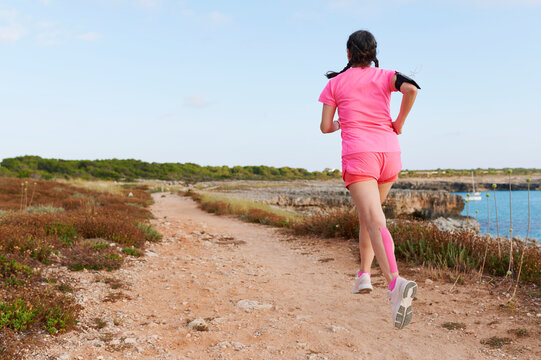 Woman running on a trail by the ocean