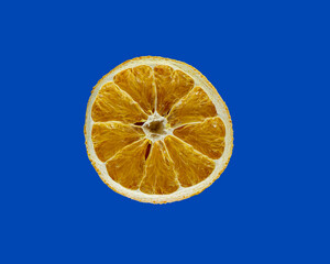 Half a dried orange on a blue background. Ingredient concept