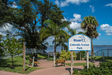 Downtown historic Stuart, Florida. Entrance to Colorado Avenue Park Healthy Trail Walk, blue sky with clouds, sunny day, lush green tropical palm trees