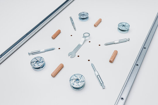 Flat lay top view of stainless steel eccentric and fastening dowels, wooden rods and spanner. Furniture assembly and household repair concept