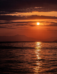 Fototapeta premium orange fiery sundwn sky with some clouds over calm sea, nature background
